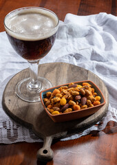 Glass of Belgian abbey red brown beer and glass bowl with party nuts