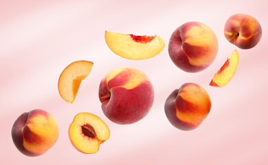 Cut and whole fresh ripe peaches falling on pink background