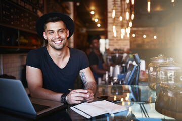 Portrait, smile and man in a cafe, barista and startup success with a laptop, planning and manager. Face, male employee and entrepreneur with a notebook, coffee shop and business owner with happiness