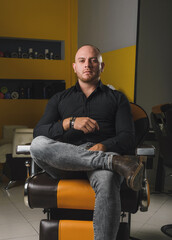 Portrait of a barber sitting in a barber's chair in his workplace.