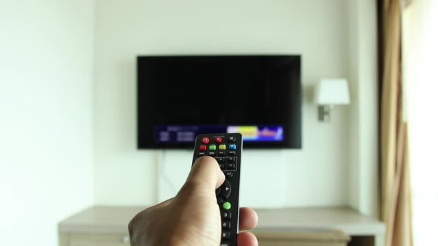 Close up of hand holding the TV remote control and changing channels