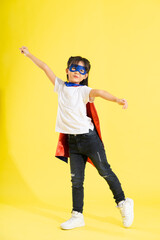 Portrait of little girl dressed up as a hero, isolated on yellow background