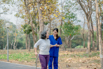 Fototapeta premium woman physiotherapist is holding a female elderly patient walking in a park to strengthen her leg muscles.