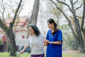 Fototapeta premium woman physiotherapist is holding a female elderly patient walking in a park to strengthen her leg muscles.