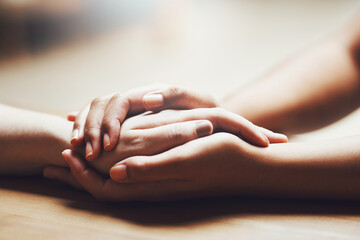 Prayer, empathy and support with people holding hands in comfort, care or understanding on a wooden table of a home. Love, faith or depression with friends closeup for help, hope or peace for healing - obrazy, fototapety, plakaty