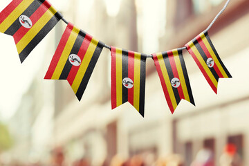 A garland of Uganda national flags on an abstract blurred background