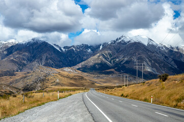 Snow capped mountains in prominence to a highway and power lines in Canterbury New Zealand