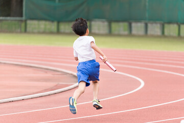 Fototapeta premium 陸上大会でリレーを走る小学生の男の子