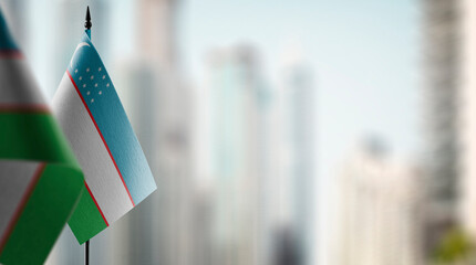 Small flags of the Uzbekistan on an abstract blurry background