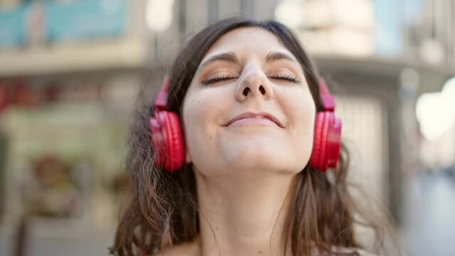 Young beautiful hispanic woman smiling confident listening to music at street