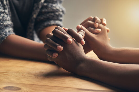 Love, partnership and couple holding hands for support, unity and sympathy by wood table. Empathy, care and couple or friends with affection in an intimate bonding moment together for grief and loss.