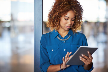 Corporate, young latino businesswoman with tablet and standing in office. Communication or networking, contact and mockup with black female worker on mobile device reading or writing email at work © Thurstan H/peopleimages.com