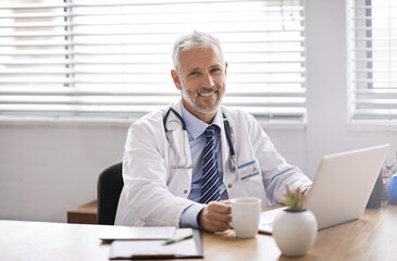 Happy, laptop and portrait of a male doctor in his office doing diagnosis research in a hospital. Confidence, success and professional mature man healthcare worker with a computer in medical clinic.