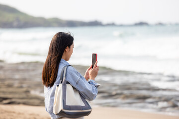 Fototapeta na wymiar Woman use cellphone to take photo beside the sea