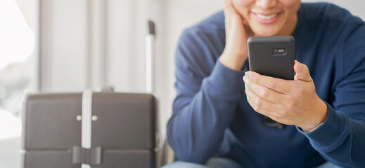 close up young asian man hold smartphone to use social media network application for reading or check feedback or watch entertainment on website while waiting in airport lounge for travel life concept