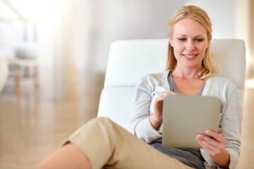 Happy woman, tablet and smile in living room for social media, research or browsing on chair at...