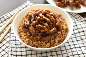 Crispy shredded beef with sweet chilli sauce with egg fried rice in a white bowl. Traditional Chinese food.