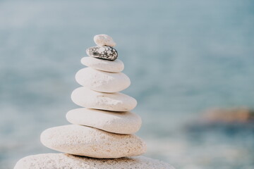 Pyramid stones on the seashore on a sunny day on the blue sea background. Happy holidays. Pebble beach, calm sea, travel destination. Concept of happy vacation on the sea, meditation, spa, calmness.