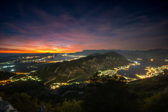 Bay of Kotor lights taken from mountain at late sunset with orange and purple sky