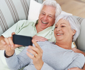 Senior, happy couple and relax for selfie on sofa in living room with smile for photo, memory or profile picture at home. Elderly man and woman smiling for photograph, vlog or social media on couch