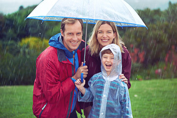 Happy family, child and portrait in rain with umbrella in nature outdoor for fun, happiness and...