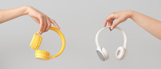 Female hands with different wireless headphones on light background