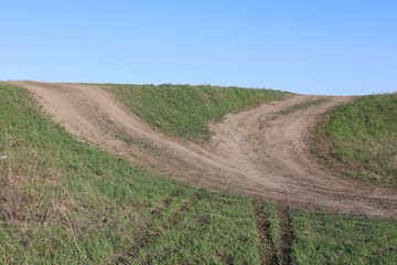 Fototapeta premium Outdoor nature landscape of two diverging dirt trails ascending a small hill, depicting the environmental damage caused by off road vehicles.