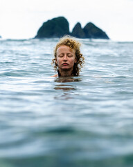 A beautiful young girl bathes in the sea, enjoying the azure coast of a tropical, paradise island.