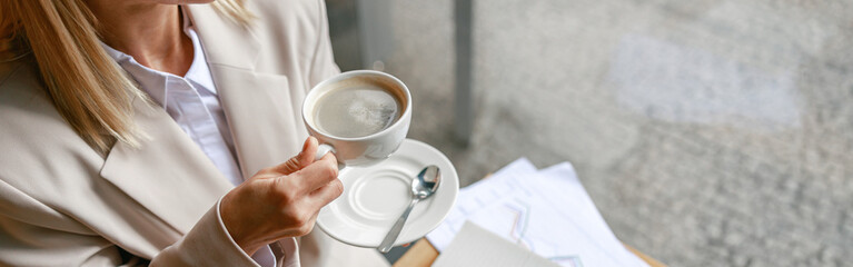 Close up of businesswoman having coffee break time during working day in cafe