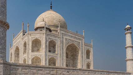 Fototapeta na wymiar Beautiful Taj Mahal against the blue sky. Symmetrical white marble mausoleum with arches, domes, minarets. There are ornaments and inlays of precious stones on the walls. India. Agra.