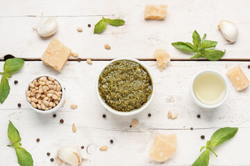 Composition with bowl of delicious pesto sauce and ingredients on white wooden table