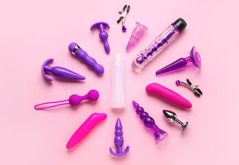 Bottle of lubricant and with vibrators and anal plugs on pink background