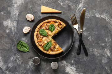 Mushroom pie with spinach leaves and cutlery on black grunge table