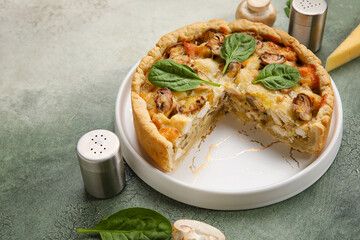 Mushroom pie with spinach leaves and champignons on green grunge table