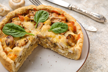 Mushroom pie with spinach leaves and cutlery on white grunge table