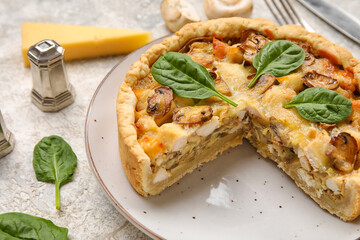 Mushroom pie with spinach leaves and cutlery on white grunge table