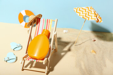 Creative composition with miniature deckchair, umbrella and sunscreen on beach