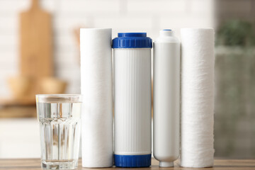 Glass of water with filters on wooden table in kitchen