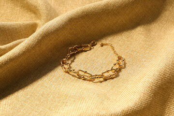 Beautiful chain bracelet on beige fabric background
