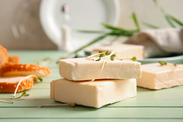 Processed cheese with herbs on green wooden background