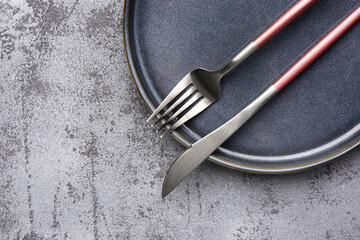 Plate with cutlery on grunge grey background