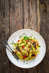 Rigatoni with sliced sausages, parmesan cheese and white mushrooms served on wooden table
