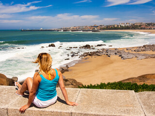 Woman sitting by the sea at Porto viewpoint
