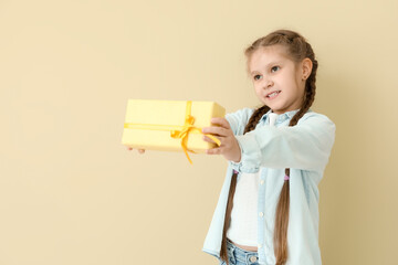 Little girl with gift box on beige background. Children's Day celebration