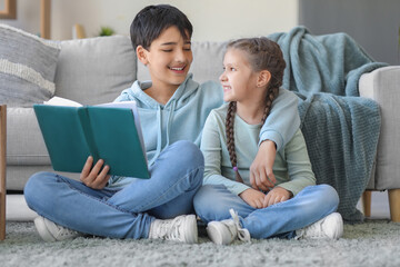 Little boy with his sister reading story at home