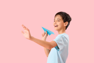 Little boy with paper plane on pink background. Children's Day celebration