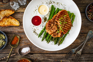 Barbecued pork neck and asparagus on wooden table
