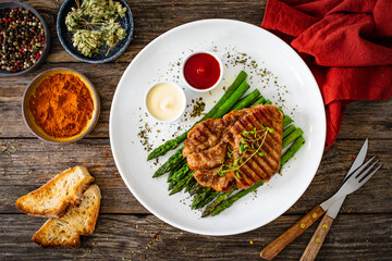 Barbecued pork neck and asparagus on wooden table