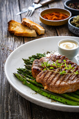 Barbecued pork neck and asparagus on wooden table