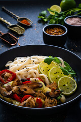 Chicken nuggets with noodles and stir fried vegetables on black table
